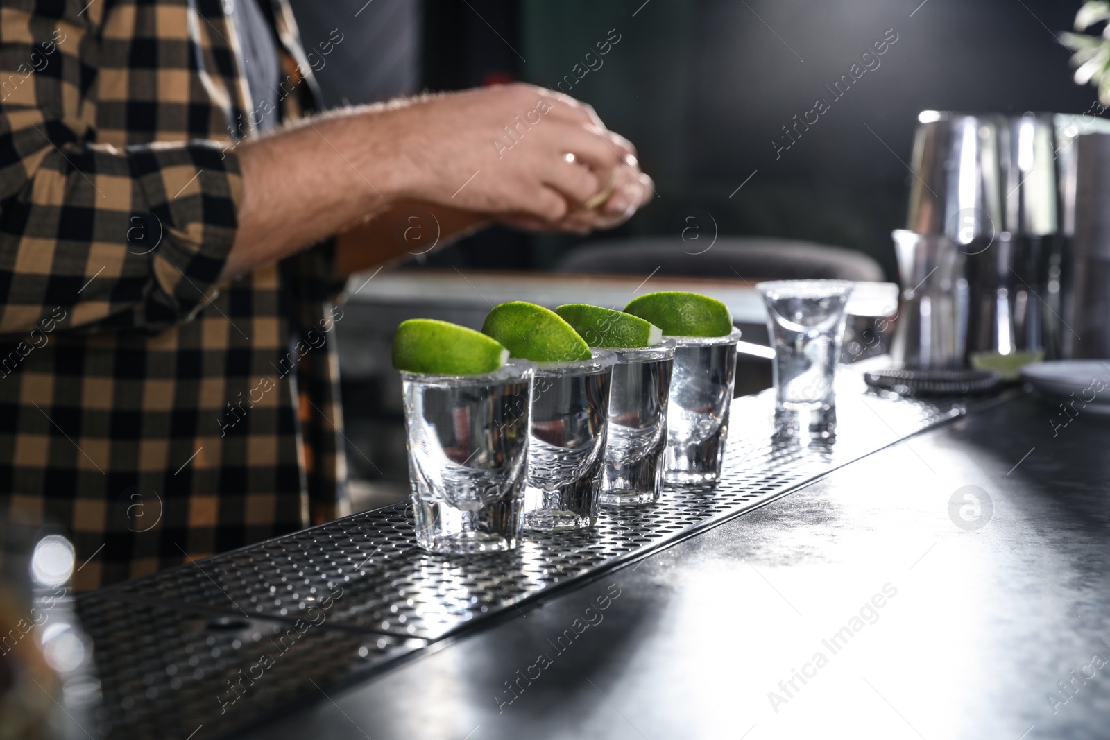 Photo of Mexican Tequila shots with lime slices on bar counter