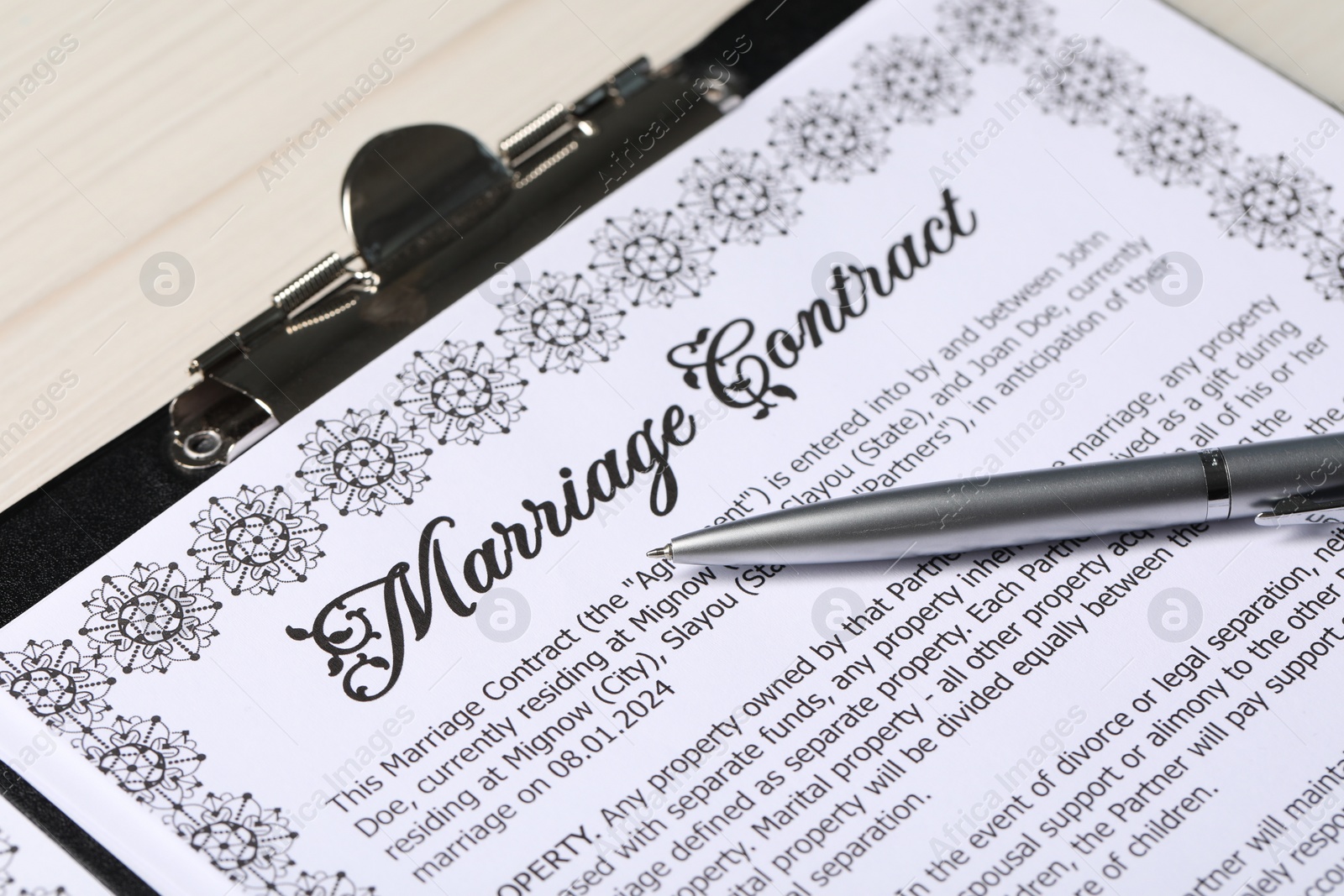 Photo of Marriage contract and pen on light wooden table, closeup
