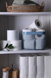 Photo of Toilet paper rolls, green leaves, towels and cotton pads on white shelves
