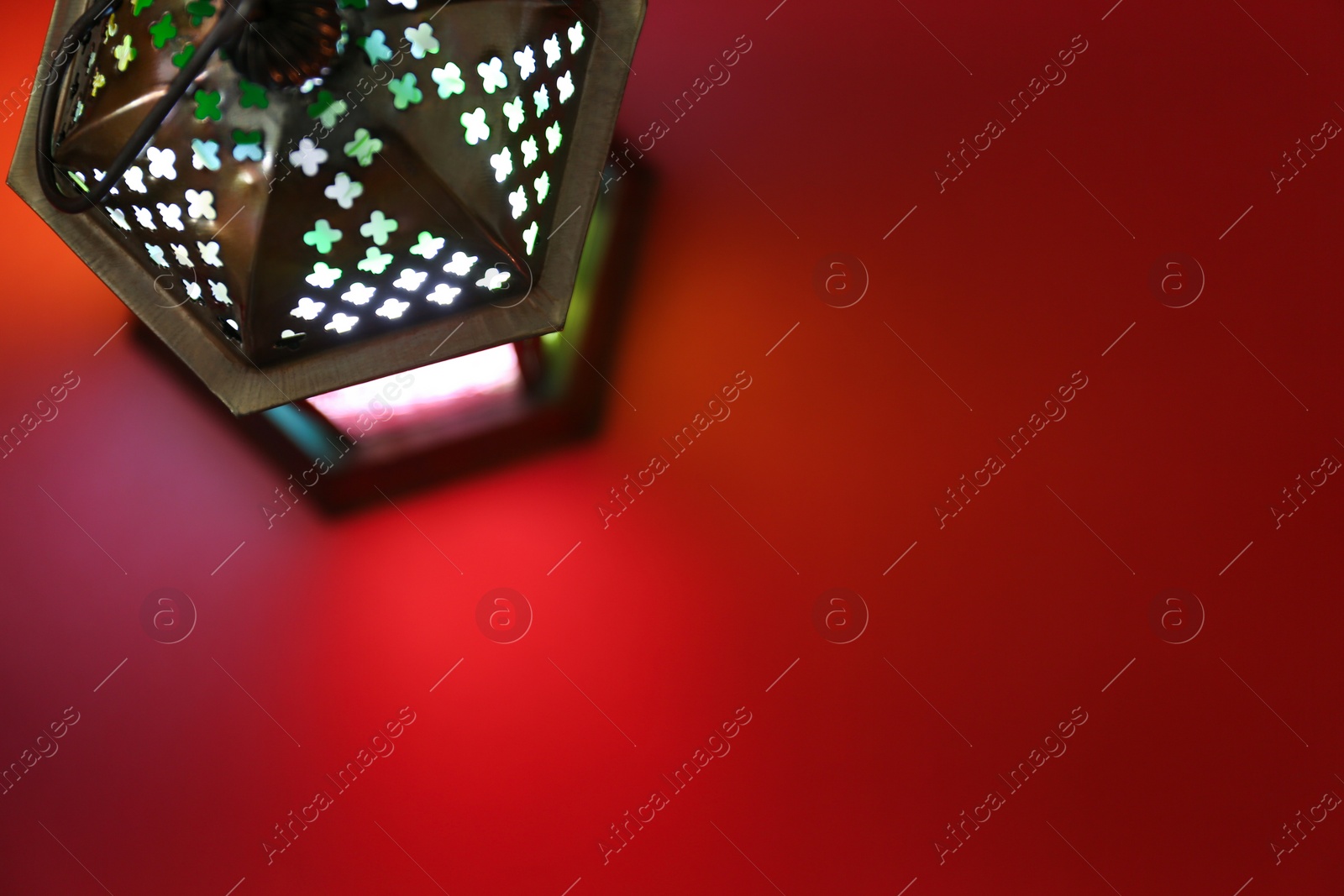 Photo of Decorative Arabic lantern on red background, top view. Space for text