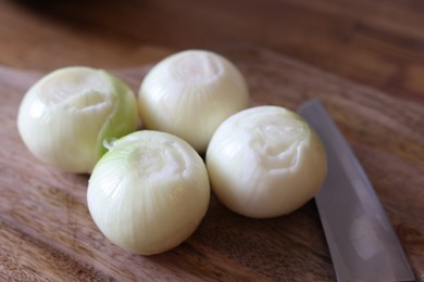 Photo of Fresh ripe onion bulbs on wooden table, closeup