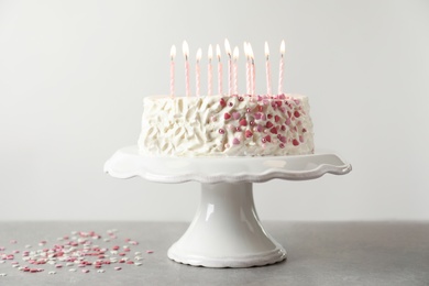 Birthday cake with candles on table against light background