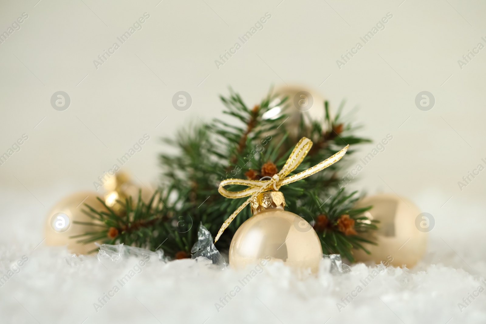 Photo of Beautiful Christmas balls and fir branch on snow against white background