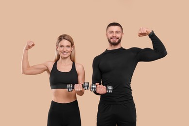 Photo of Athletic people with dumbbells showing muscles on light brown background