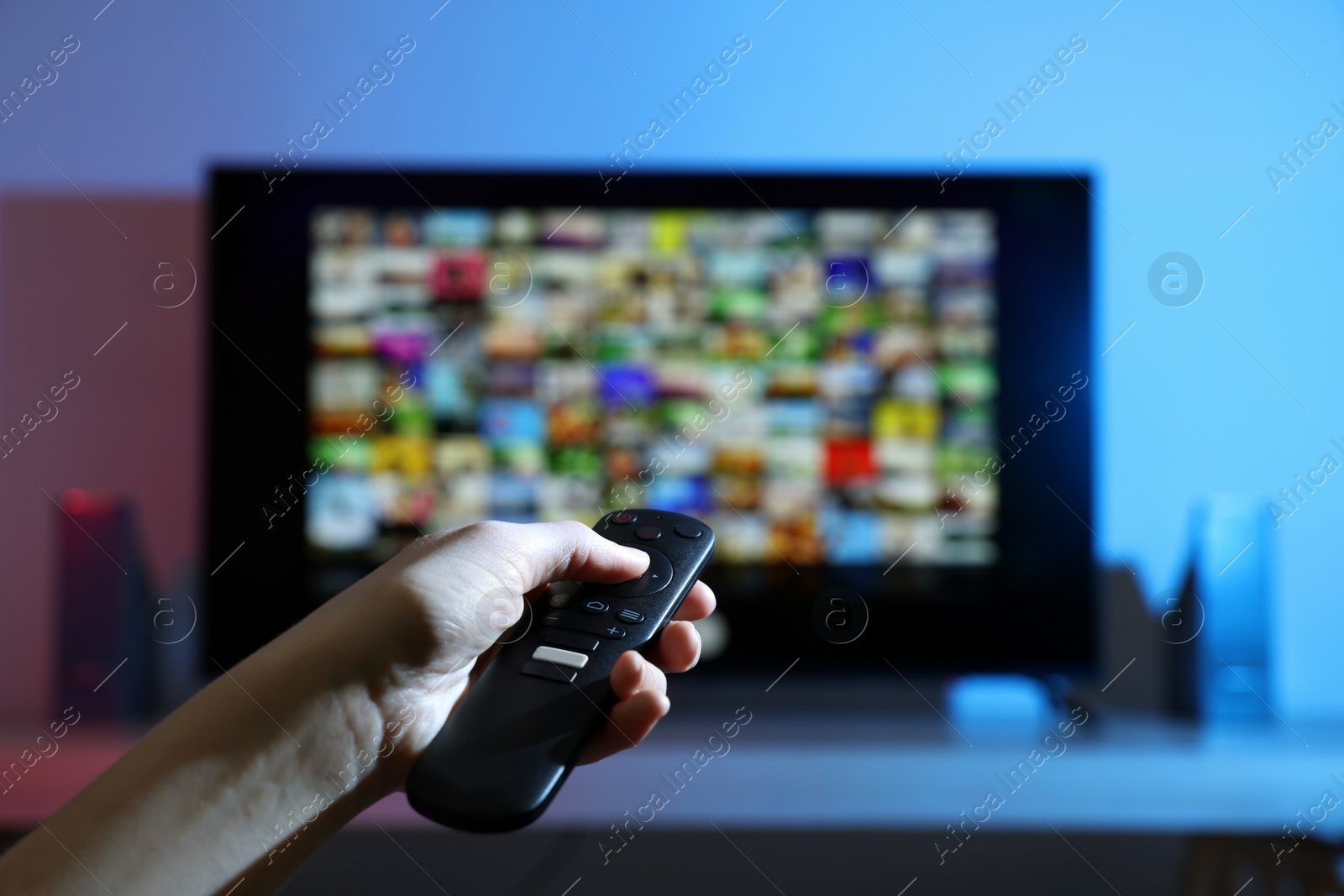 Photo of Woman switching channels on TV set with remote control at home, closeup