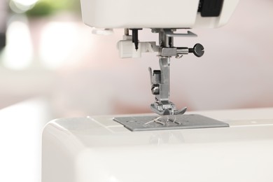 Photo of Modern sewing machine in atelier, closeup view