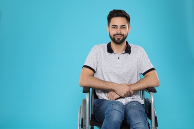 Young man in wheelchair on color background. Space for text