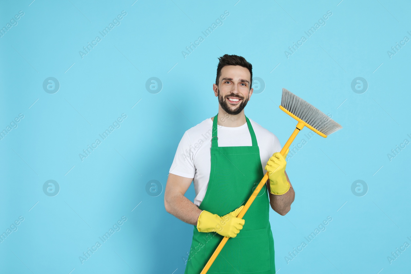 Photo of Man with yellow broom on light blue background, space for text