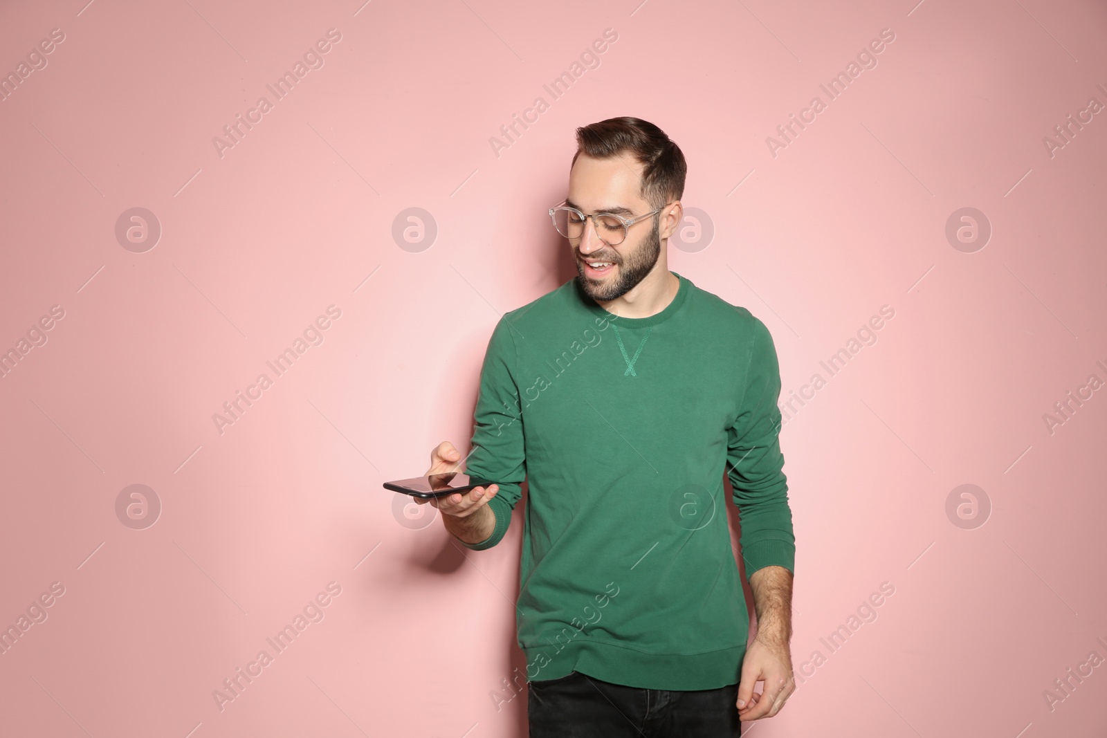 Photo of Handsome young man with mobile phone on color background