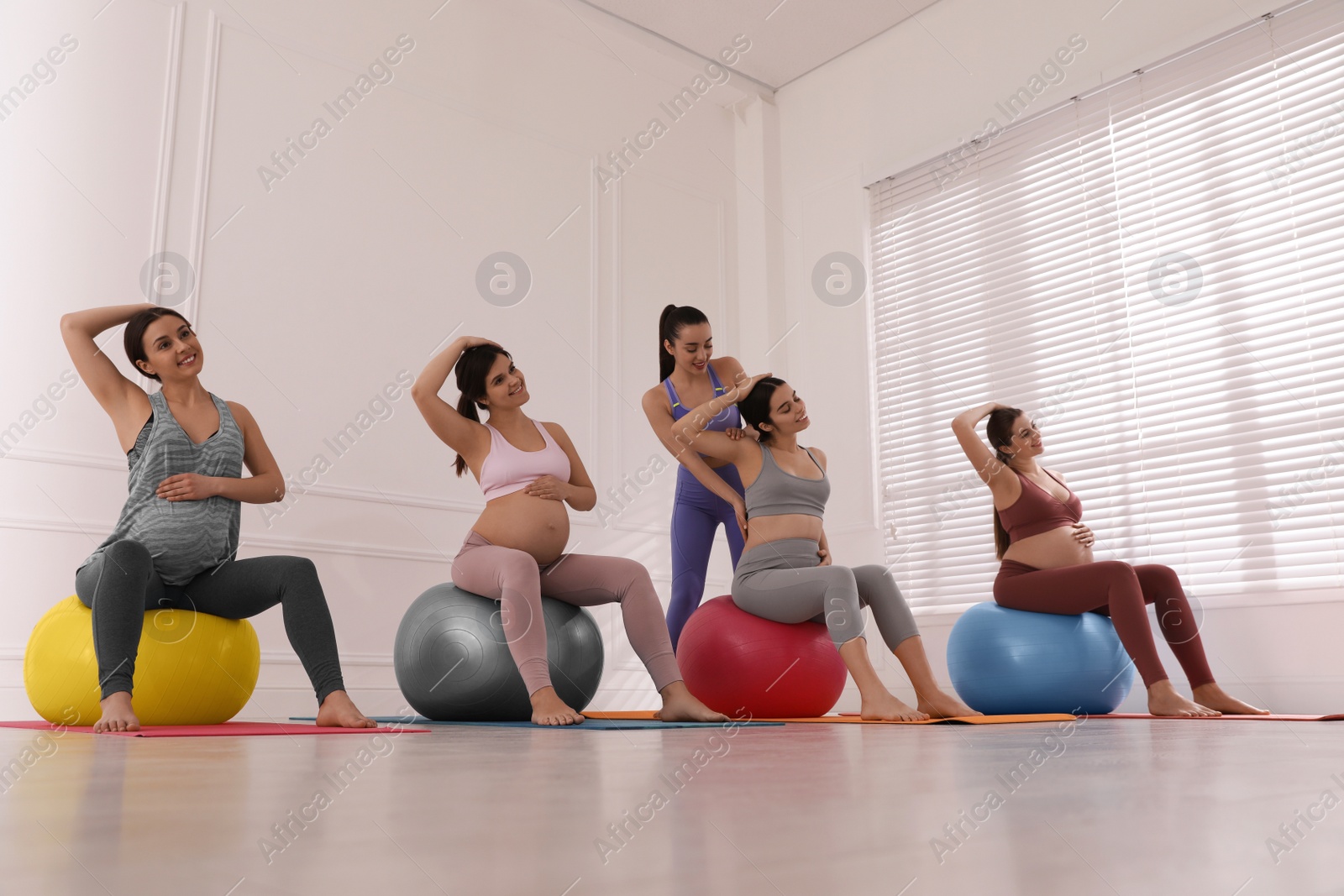 Photo of Trainer working with group of pregnant women in gym. Preparation for child birth