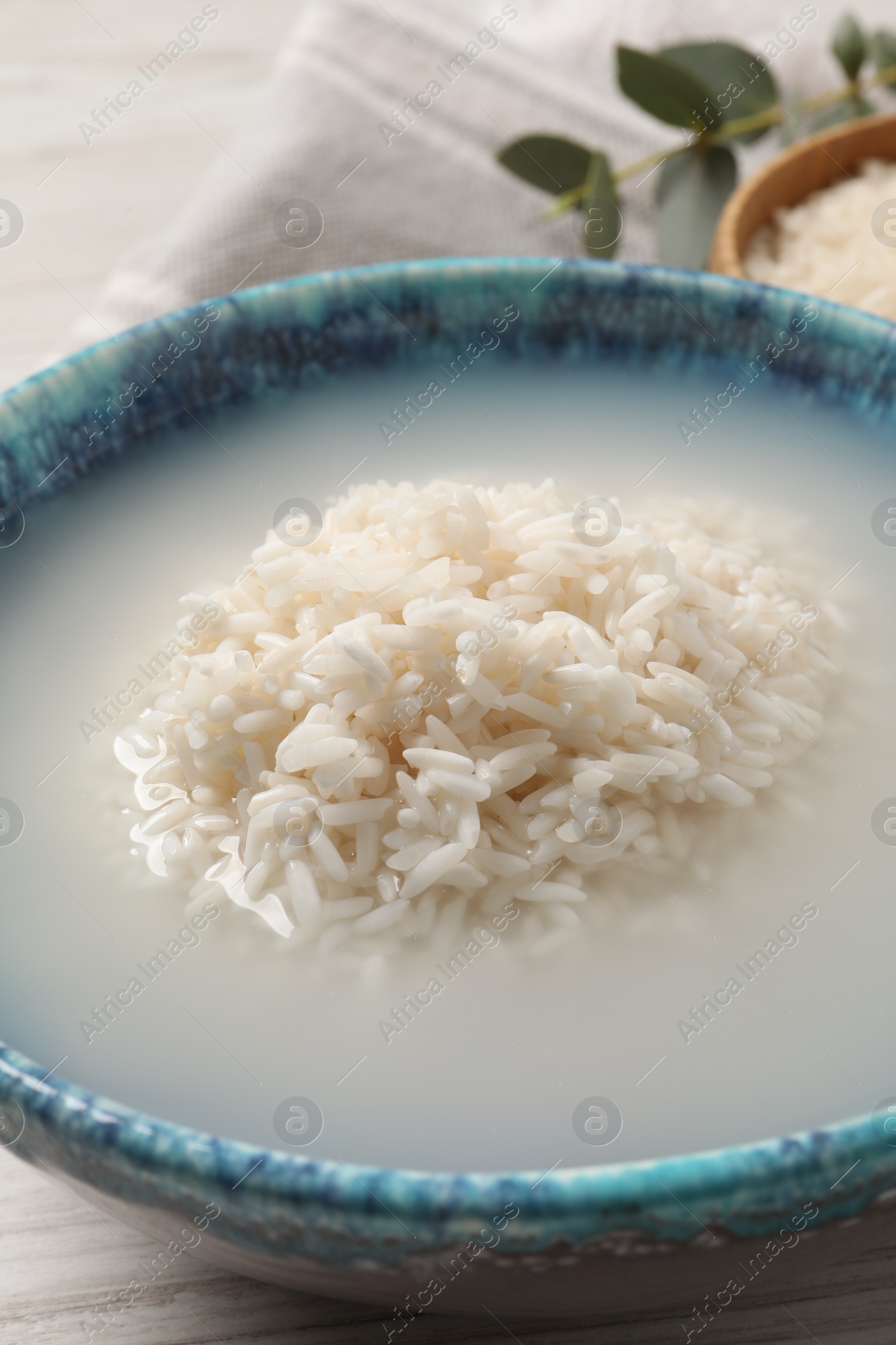 Photo of Bowl with rice soaked in water on table, closeup