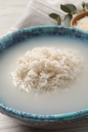 Photo of Bowl with rice soaked in water on table, closeup