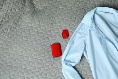 Photo of Male stick deodorant and light blue shirt on grey plaid, flat lay. Space for text