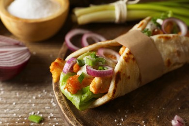 Photo of Delicious pita wrap with meat and vegetables on wooden table, closeup