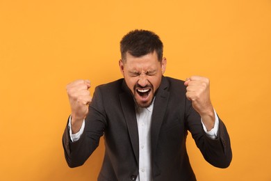 Photo of Aggressive man shouting on orange background. Hate concept