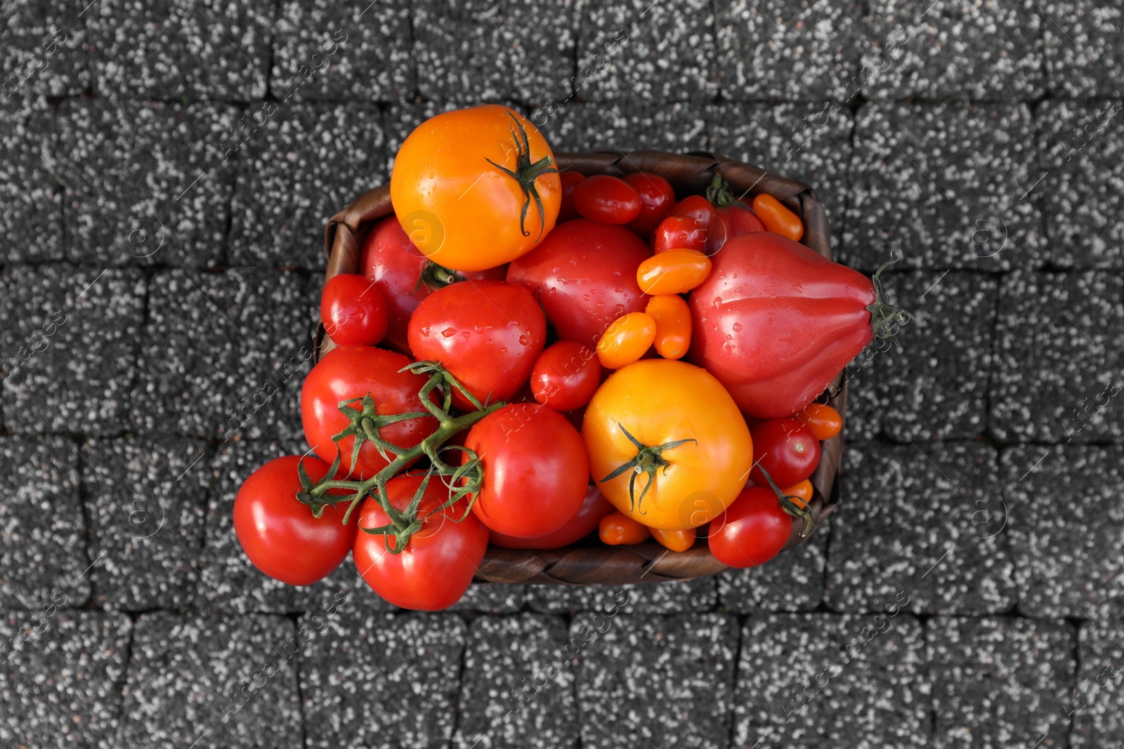 Photo of Basket with fresh tomatoes on stone surface, top view