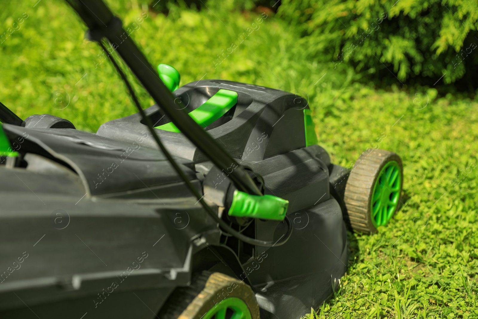Photo of Lawn mower on green grass in garden, closeup
