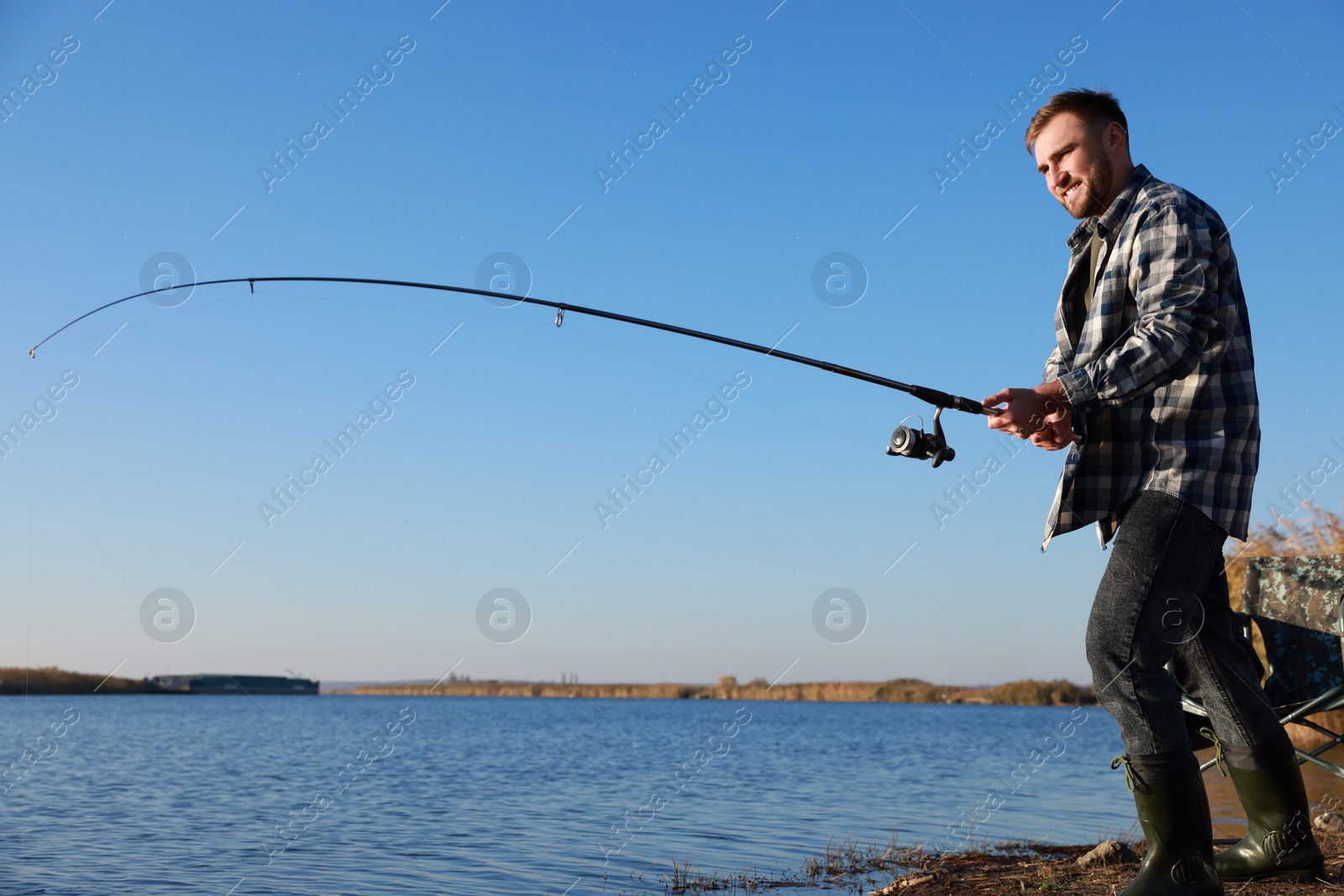 Photo of Fisherman with rod fishing at riverside. Recreational activity