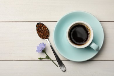 Cup of delicious chicory drink, granules and flower on white wooden table, flat lay