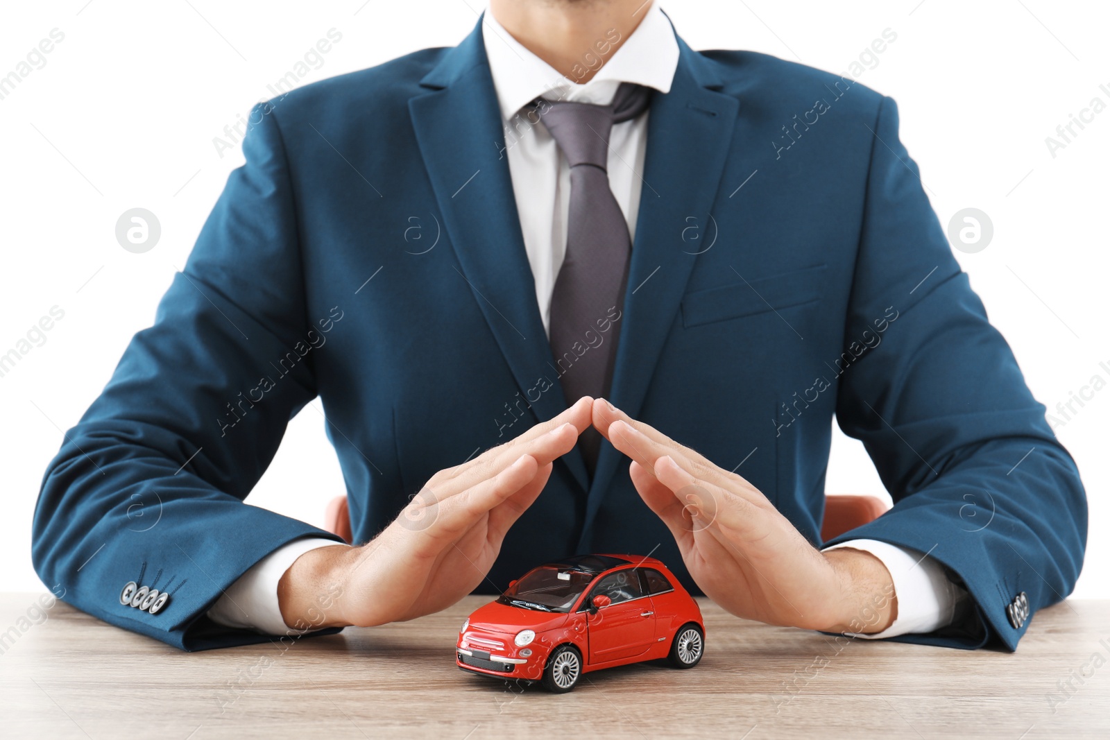 Photo of Insurance agent covering toy car on table against white background