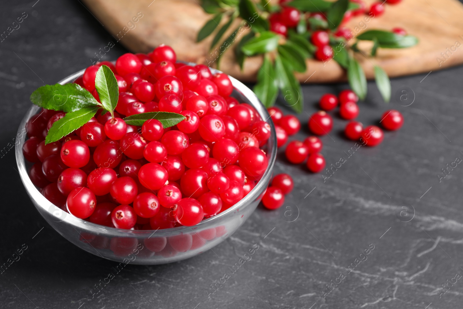 Photo of Fresh cranberry in bowl on dark grey table, space for text