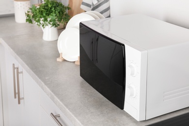 Photo of Modern microwave oven on table in kitchen