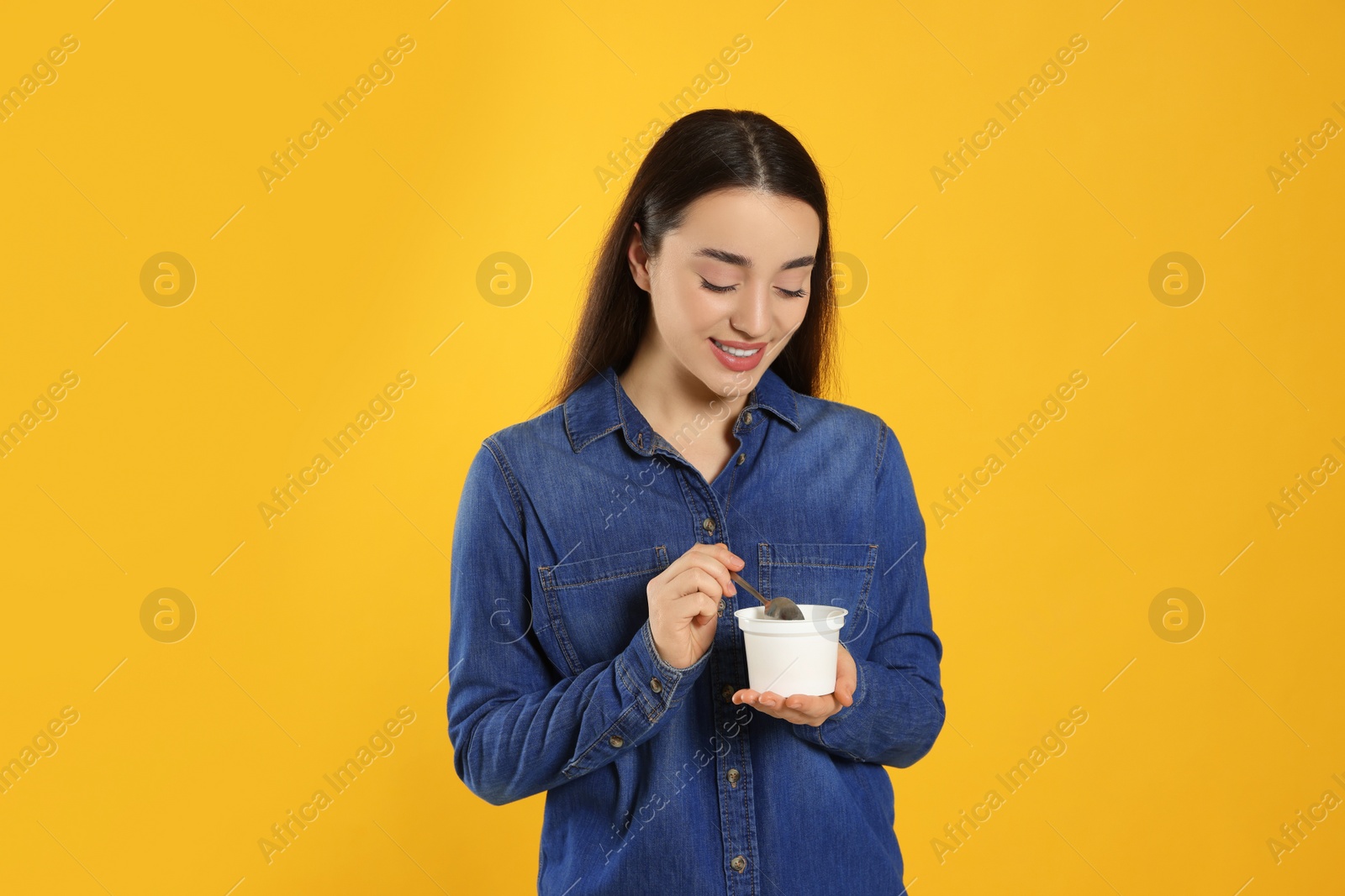 Photo of Happy woman with tasty yogurt on orange background