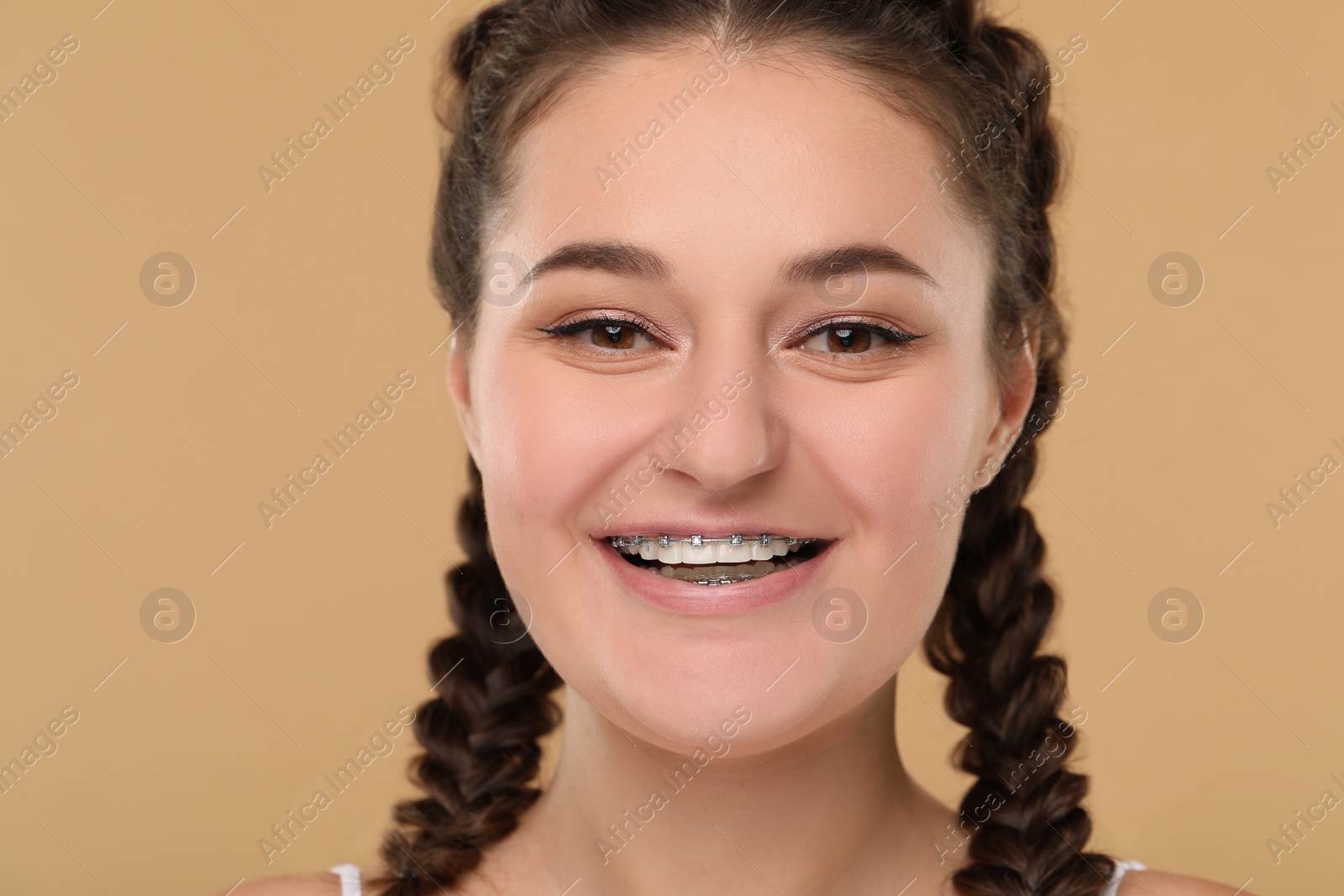 Photo of Smiling woman with dental braces on brown background
