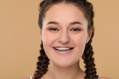 Smiling woman with dental braces on brown background