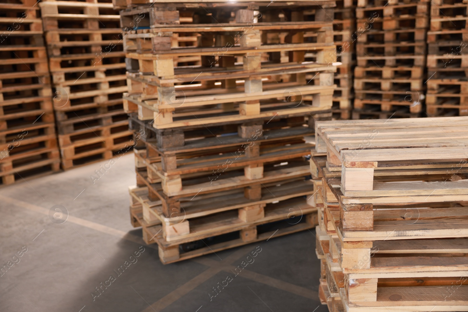 Image of Many empty wooden pallets stacked in warehouse. Space for text