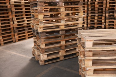 Many empty wooden pallets stacked in warehouse. Space for text