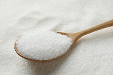 Wooden spoon on granulated sugar, closeup view