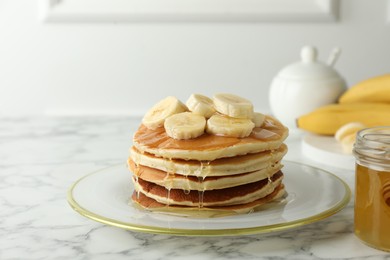 Photo of Delicious pancakes with bananas and honey on white marble table. Space for text