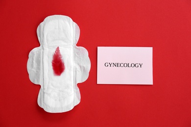 Flat lay composition with menstrual pad and red feather on color background. Gynecological care