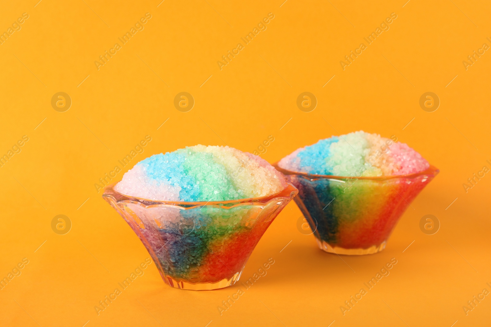 Photo of Rainbow shaving ice in glass dessert bowls on orange background