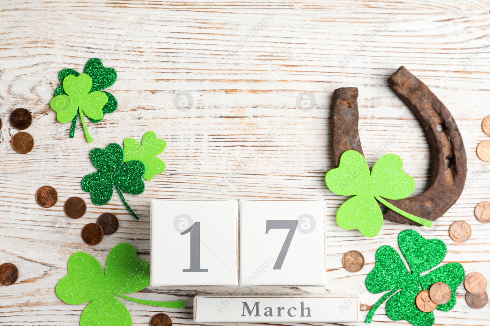 Photo of Flat lay composition with horseshoe and block calendar on white wooden background. St. Patrick's Day celebration