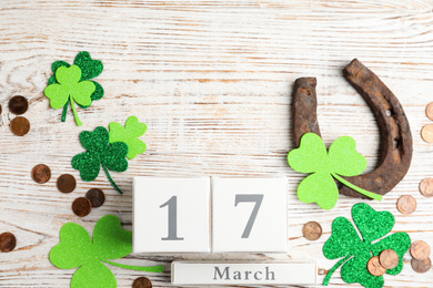 Photo of Flat lay composition with horseshoe and block calendar on white wooden background. St. Patrick's Day celebration