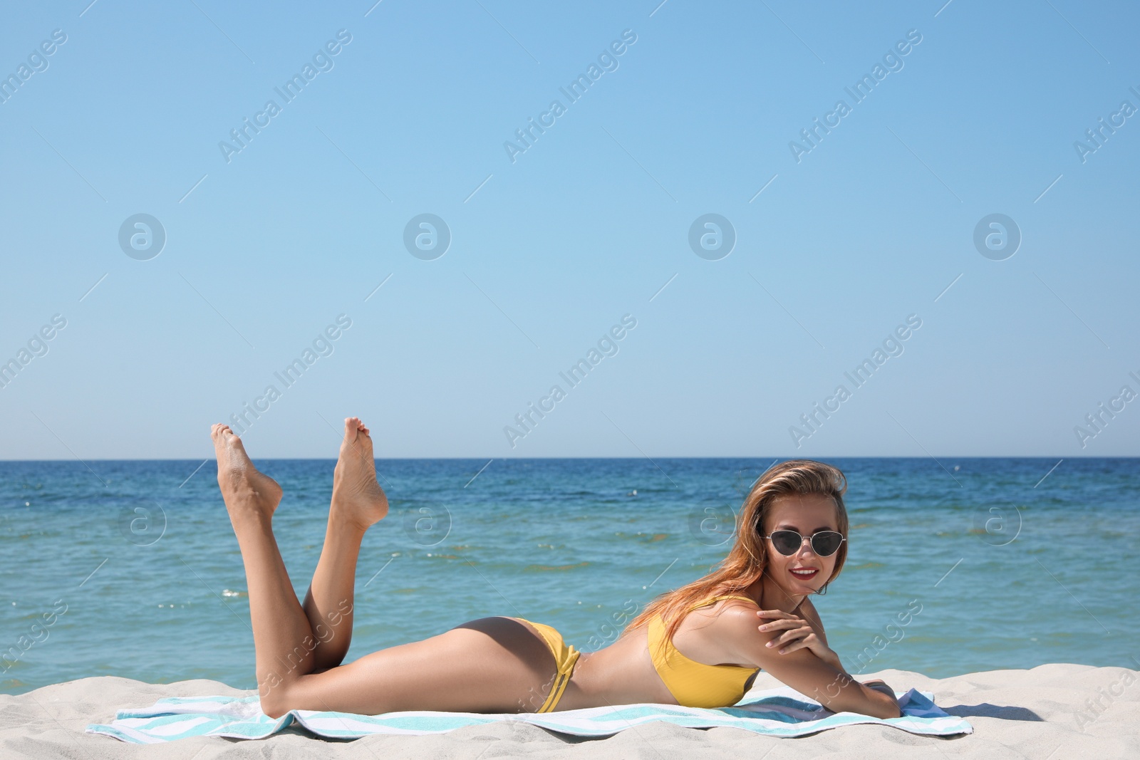 Photo of Beautiful woman with beach towel on sand near sea