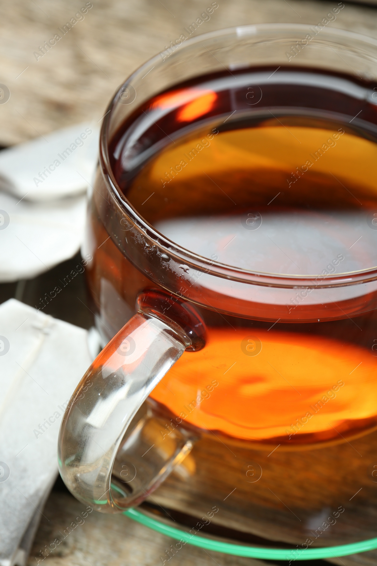 Photo of Aromatic tea in glass cup on wooden table, closeup