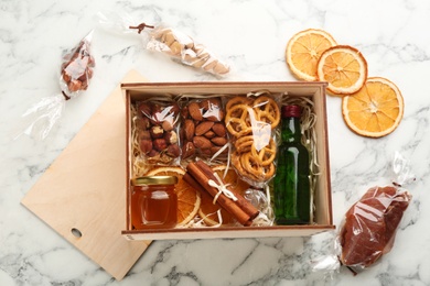 Stylish gift set in wooden box on white marble table, flat lay