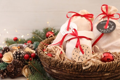 Bags with gifts in basket and festive decor on table, closeup. Christmas advent calendar