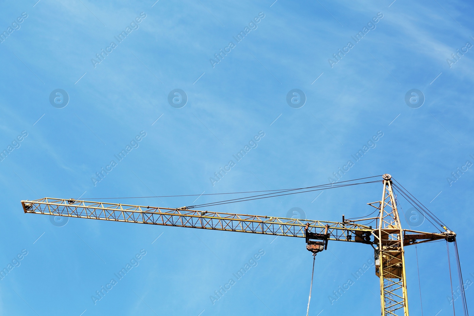 Photo of Modern tower crane against blue sky. Construction site, low angle view