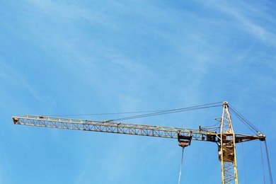 Modern tower crane against blue sky. Construction site, low angle view