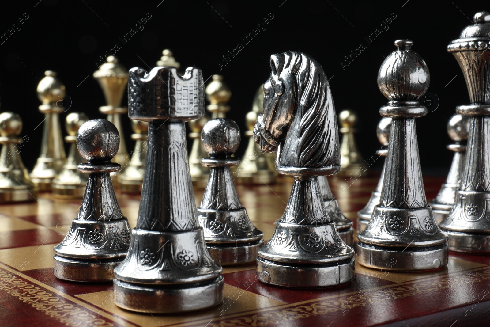 Photo of Chessboard with game pieces on black background, closeup