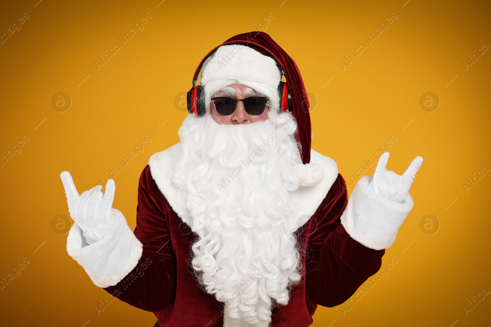 Photo of Santa Claus with headphones listening to Christmas music on yellow background