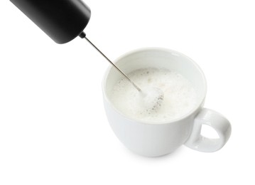 Whisking milk in cup with mini mixer (frother wand) isolated on white, closeup