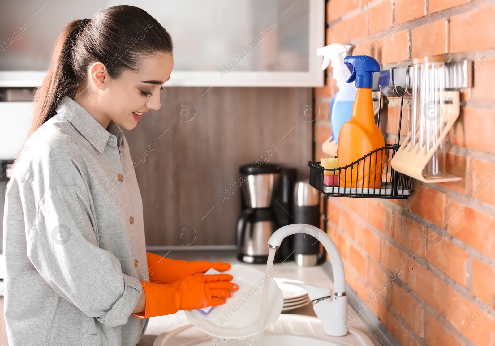 Photo of Young woman washing dishes in kitchen