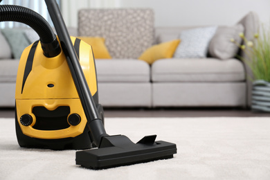 Modern yellow vacuum cleaner on carpet indoors, space for text