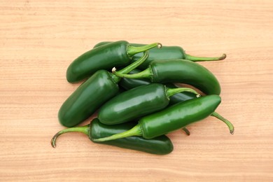Photo of Pile of fresh ripe green jalapeno peppers on wooden table