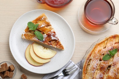 Slice of traditional apple pie served on wooden table, flat lay